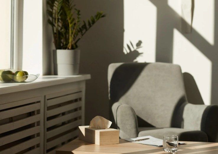 Rincón de terapia con butaca, planta y luz natural en la consulta de Toledo